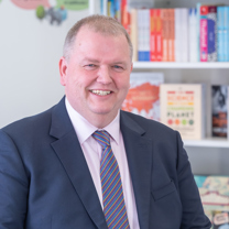 Photo of man smiling, in front of a bookcase