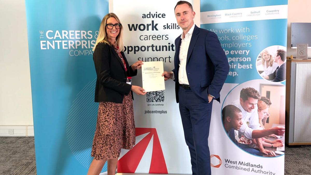 Two people holding a partnership certificate in front of The Careers & Enterprise Company and West Midlands Careers Hub banners.