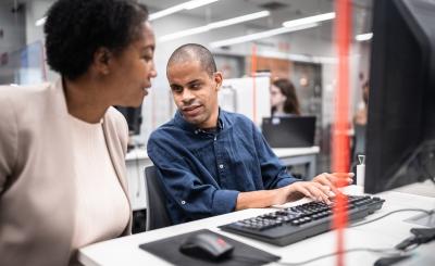 woman supporting worker who is visually impaired to use computer 