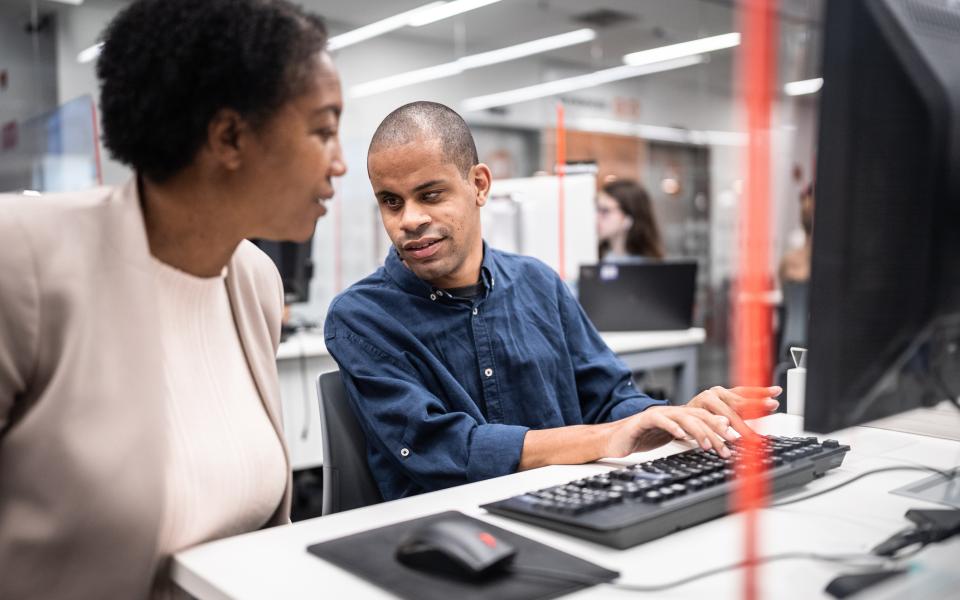 woman supporting worker who is visually impaired to use computer 